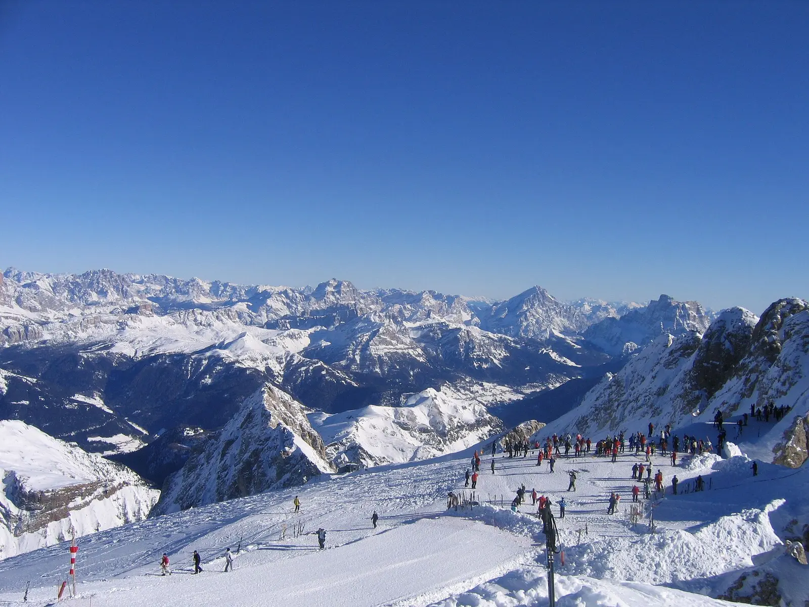 Skiers on a snowy slope above Alta Badia with the Dolomites beyond