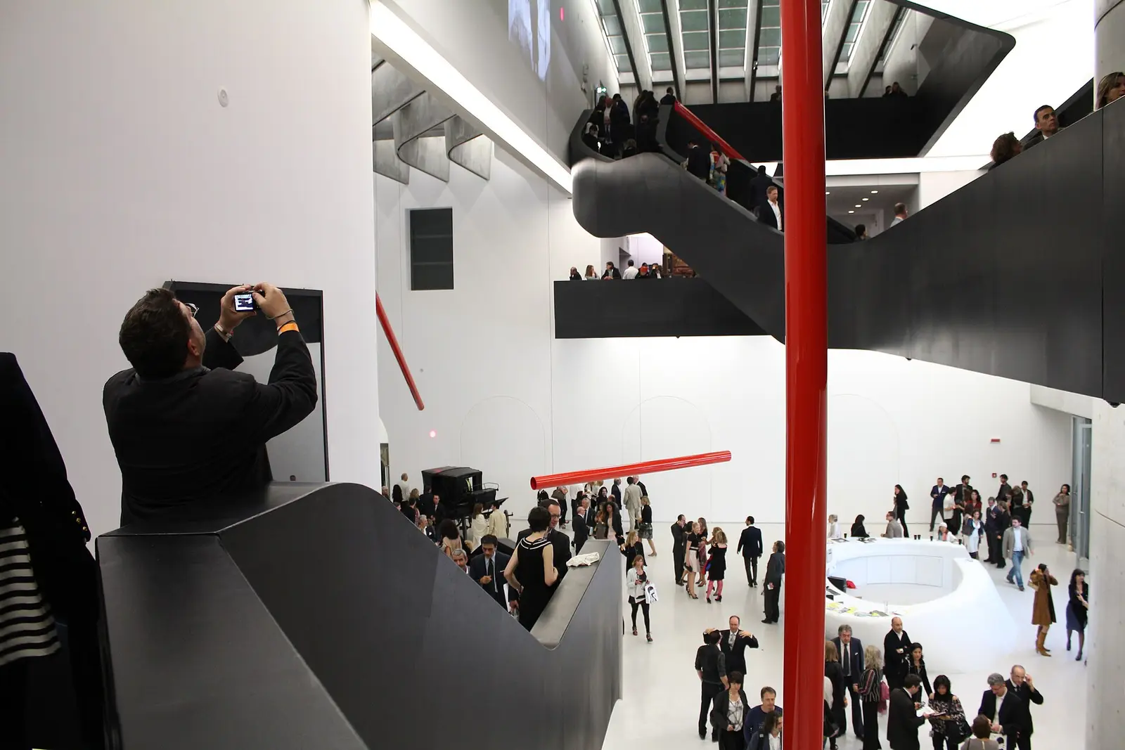 Visitors in the white atrium of the MAXXI museum with its steel stairways