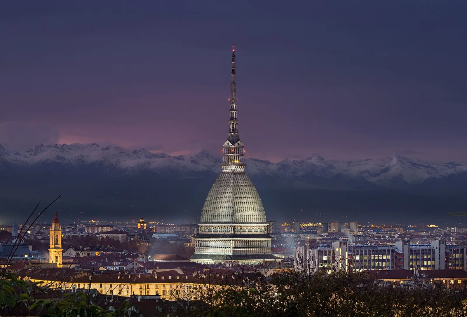 The Mole Antonelliana tower in Turin at dusk with the Alps behind